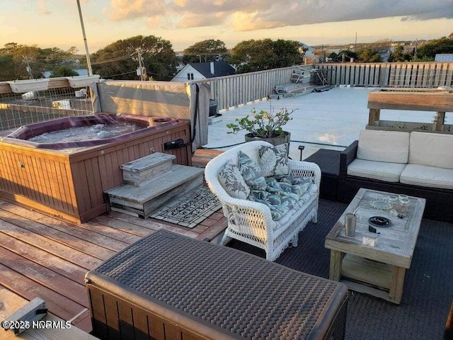 deck at dusk with a hot tub and an outdoor hangout area