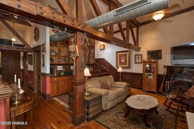 living room featuring beamed ceiling, dark hardwood / wood-style floors, high vaulted ceiling, and wood walls