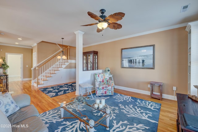 living room with crown molding, ceiling fan, hardwood / wood-style floors, and ornate columns