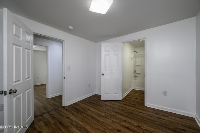 unfurnished bedroom with ensuite bath and dark wood-type flooring