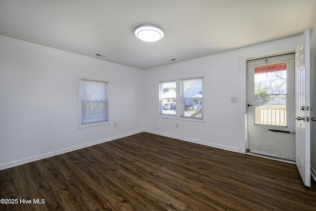 empty room with visible vents, baseboards, and dark wood-style flooring