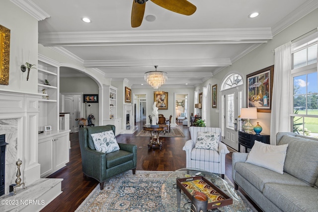 living room featuring beam ceiling, ornamental molding, dark hardwood / wood-style floors, built in features, and a fireplace