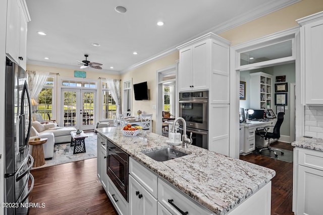 kitchen with sink, appliances with stainless steel finishes, white cabinets, a center island with sink, and french doors