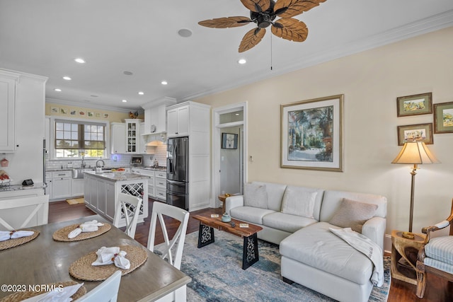 living room featuring ceiling fan, ornamental molding, dark hardwood / wood-style flooring, and sink