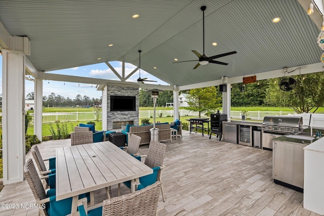 view of patio with an outdoor kitchen, a gazebo, ceiling fan, a grill, and an outdoor living space with a fireplace