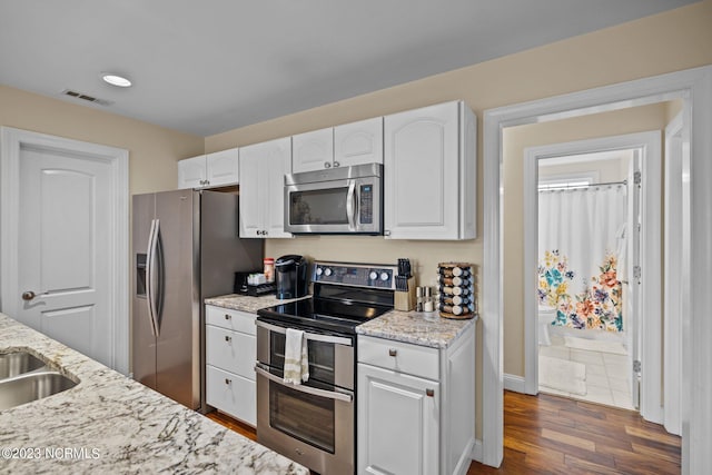 kitchen with white cabinetry, light stone countertops, dark hardwood / wood-style flooring, and stainless steel appliances