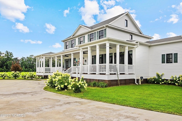 back of property with ceiling fan, a yard, and covered porch