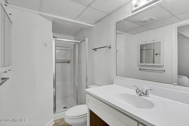 bathroom with walk in shower, a paneled ceiling, vanity, and toilet