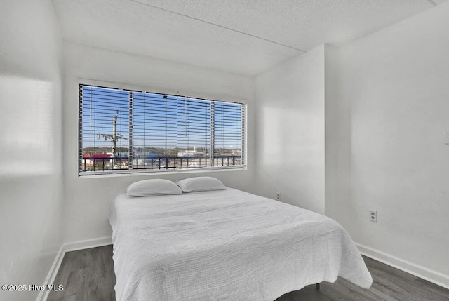 bedroom with dark hardwood / wood-style floors and a textured ceiling