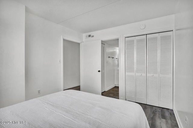 bedroom with connected bathroom, dark hardwood / wood-style floors, and a closet