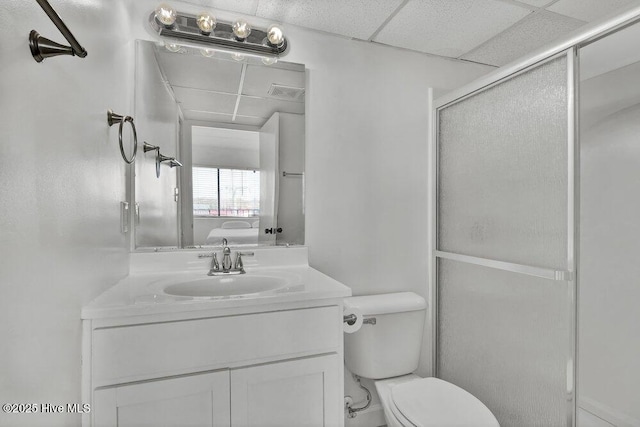 bathroom with vanity, a paneled ceiling, a shower with door, and toilet