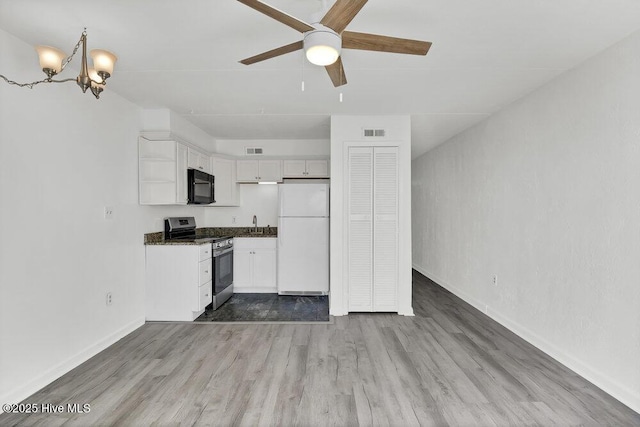 kitchen featuring stainless steel electric range, white cabinetry, white fridge, ceiling fan with notable chandelier, and light wood-type flooring