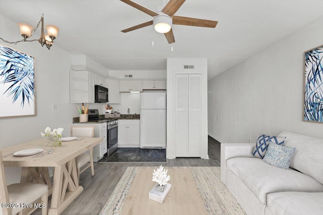 living room with dark wood-type flooring, sink, and ceiling fan with notable chandelier