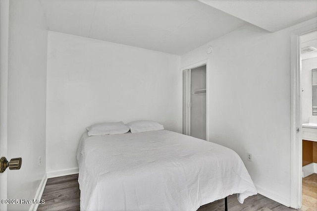 bedroom with hardwood / wood-style flooring and ensuite bathroom