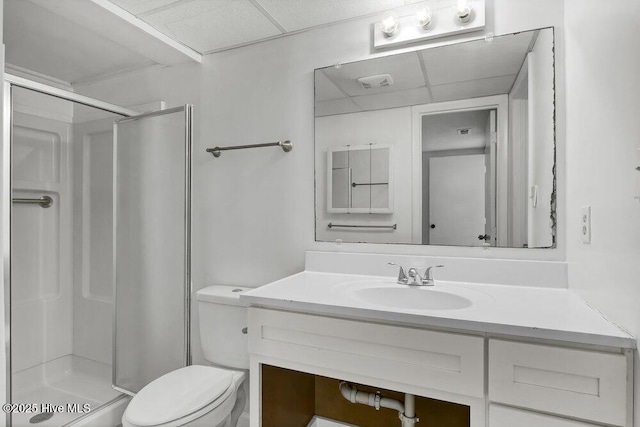 bathroom featuring a paneled ceiling, vanity, toilet, and a shower with shower door