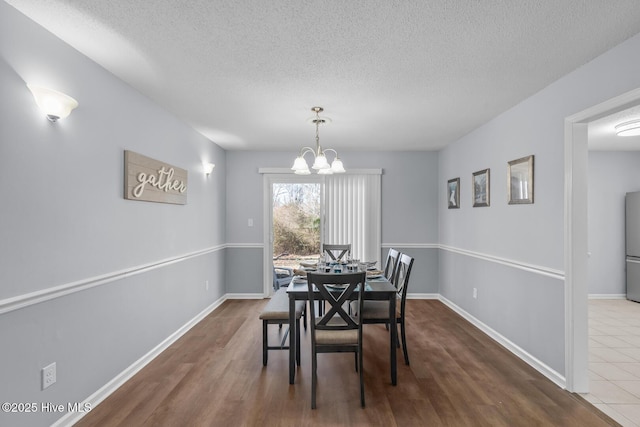 dining area featuring dark hardwood / wood-style floors, a notable chandelier, and a textured ceiling