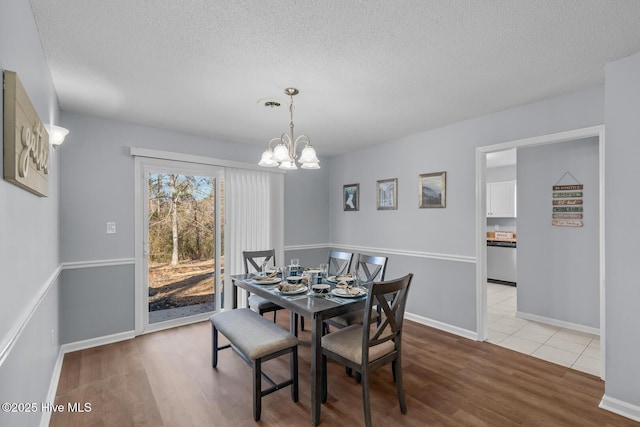 dining area featuring an inviting chandelier, a textured ceiling, and light wood-type flooring