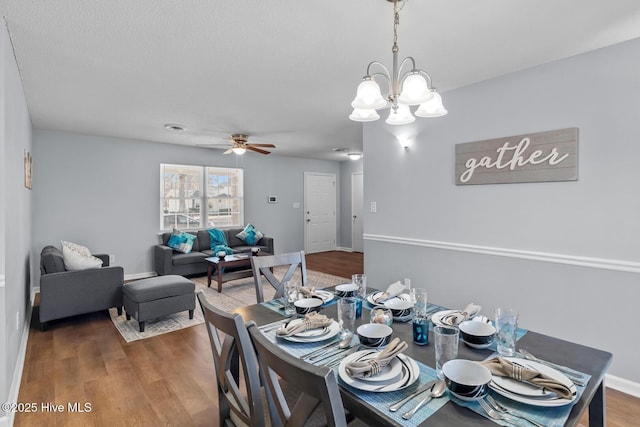 dining room with dark hardwood / wood-style flooring, ceiling fan with notable chandelier, and a textured ceiling