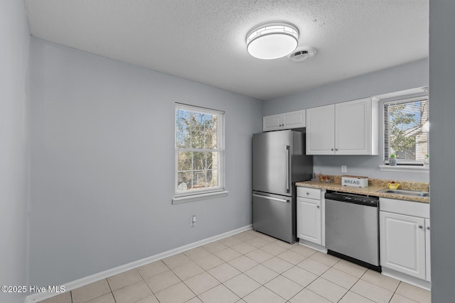 kitchen with sink, white cabinetry, a textured ceiling, light tile patterned floors, and stainless steel appliances