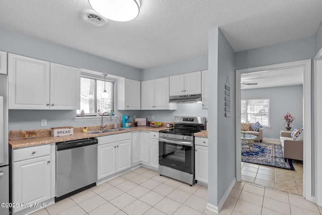 kitchen featuring sink, a textured ceiling, light tile patterned floors, appliances with stainless steel finishes, and white cabinets