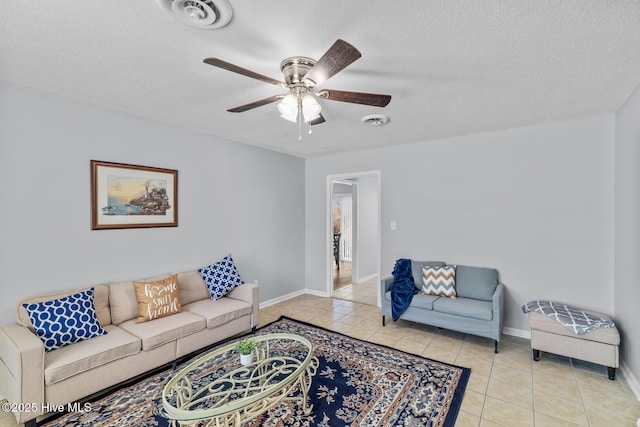 living room featuring light tile patterned flooring, ceiling fan, and a textured ceiling