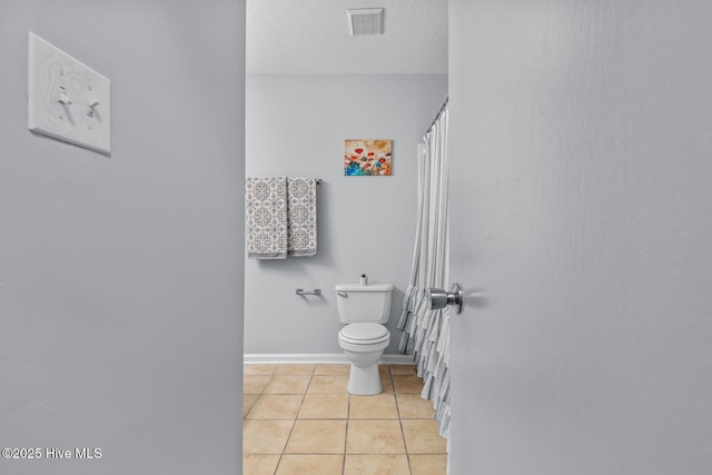 bathroom with tile patterned floors, a textured ceiling, and toilet