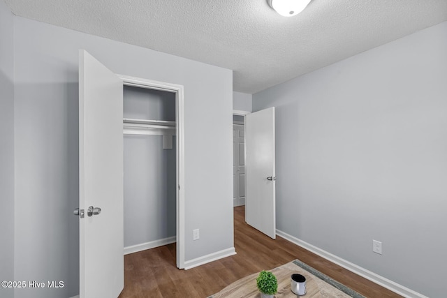 unfurnished bedroom with hardwood / wood-style flooring, a closet, and a textured ceiling