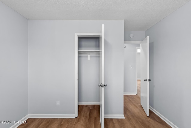 unfurnished bedroom featuring hardwood / wood-style flooring, a textured ceiling, and a closet