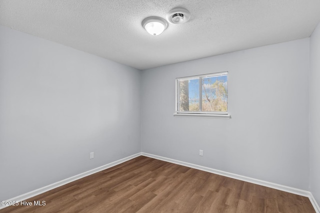 spare room featuring hardwood / wood-style flooring and a textured ceiling