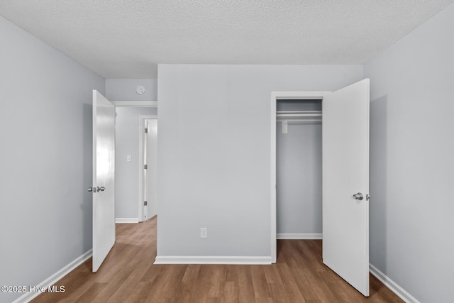 unfurnished bedroom with light hardwood / wood-style flooring, a closet, and a textured ceiling