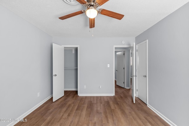 unfurnished bedroom with a walk in closet, ceiling fan, light hardwood / wood-style floors, a textured ceiling, and a closet