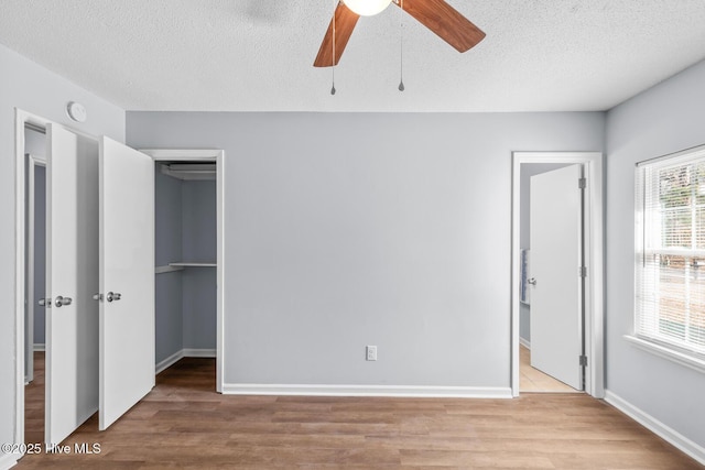 unfurnished bedroom featuring a closet, a spacious closet, light hardwood / wood-style flooring, and a textured ceiling