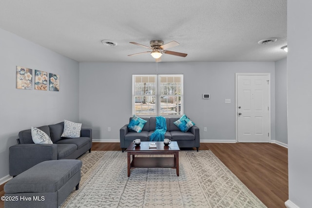 living room with ceiling fan, hardwood / wood-style flooring, and a textured ceiling