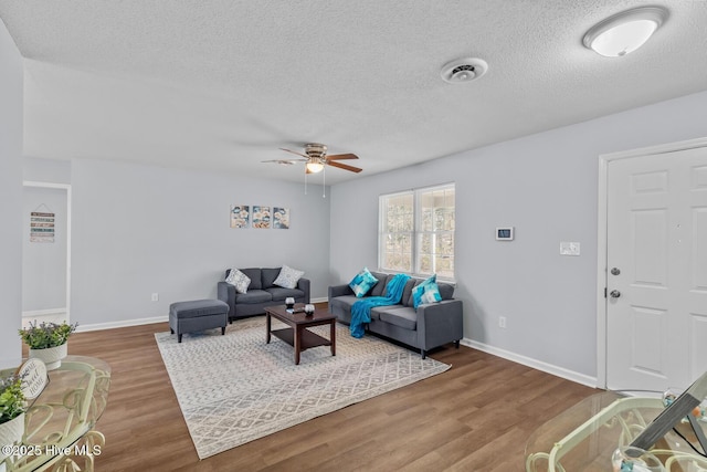 living room with wood-type flooring, ceiling fan, and a textured ceiling