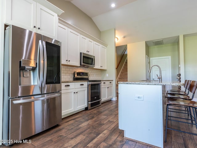 214 Admiral Ct, Sneads Ferry, NC 28460 - kitchen featuring stainless steel appliances, dark wood-type flooring, vaulted ceiling, white cabinetry, and backsplash