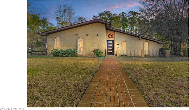 view of front of home featuring a front lawn, fence, and brick siding