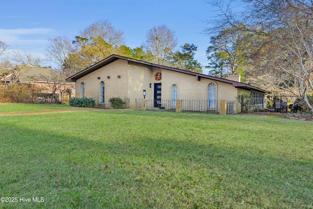 exterior space featuring a yard, brick siding, a chimney, and fence