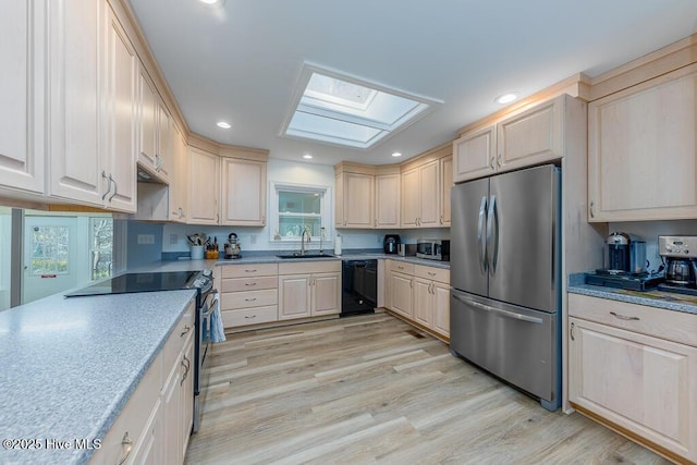 kitchen featuring stainless steel appliances, a skylight, sink, and light hardwood / wood-style flooring