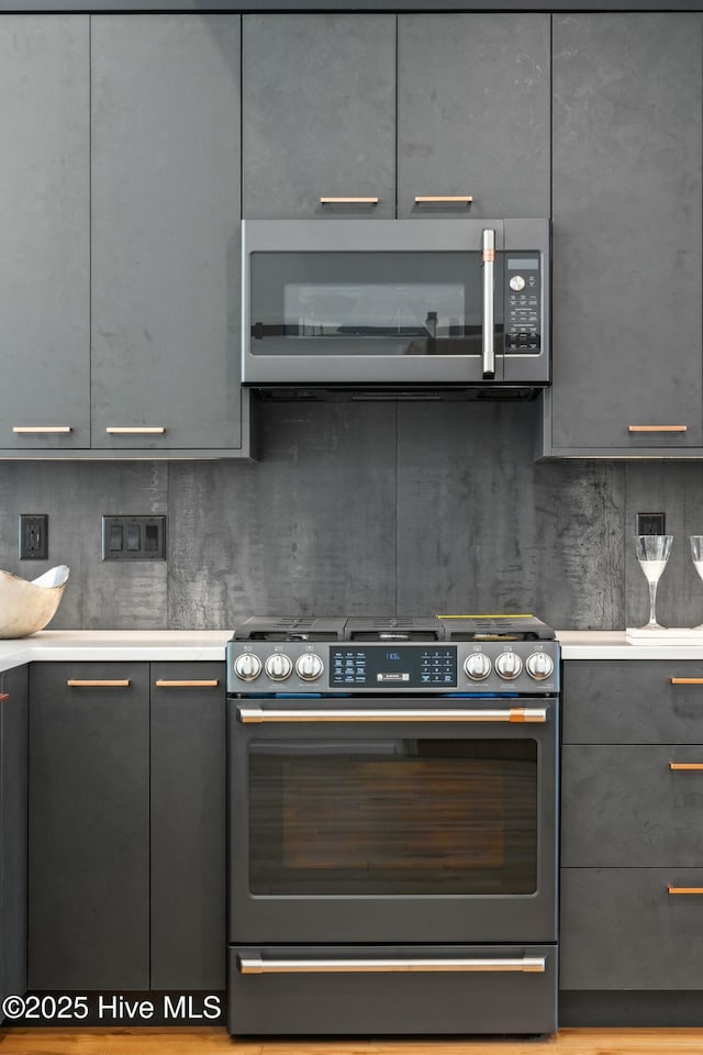 kitchen with gray cabinets, gas stove, and decorative backsplash