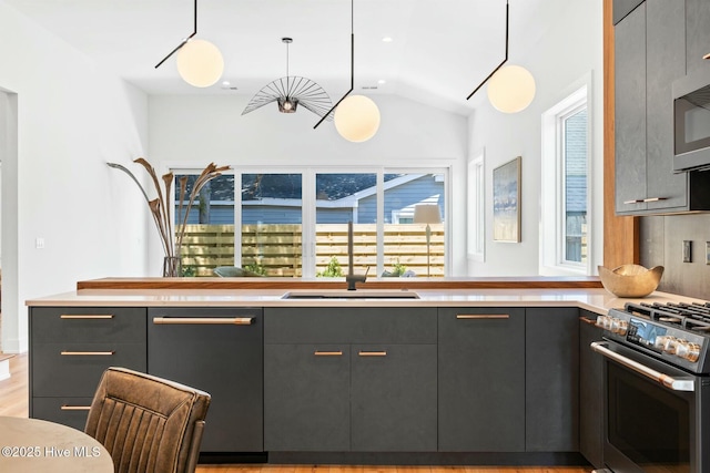 kitchen featuring appliances with stainless steel finishes, decorative light fixtures, lofted ceiling, sink, and gray cabinetry