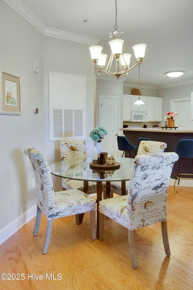 dining room featuring ornamental molding, an inviting chandelier, and light wood-type flooring