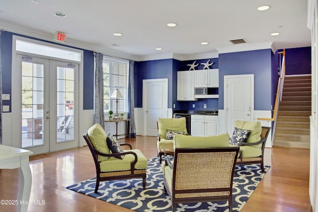 living room with ornamental molding, light hardwood / wood-style floors, and french doors