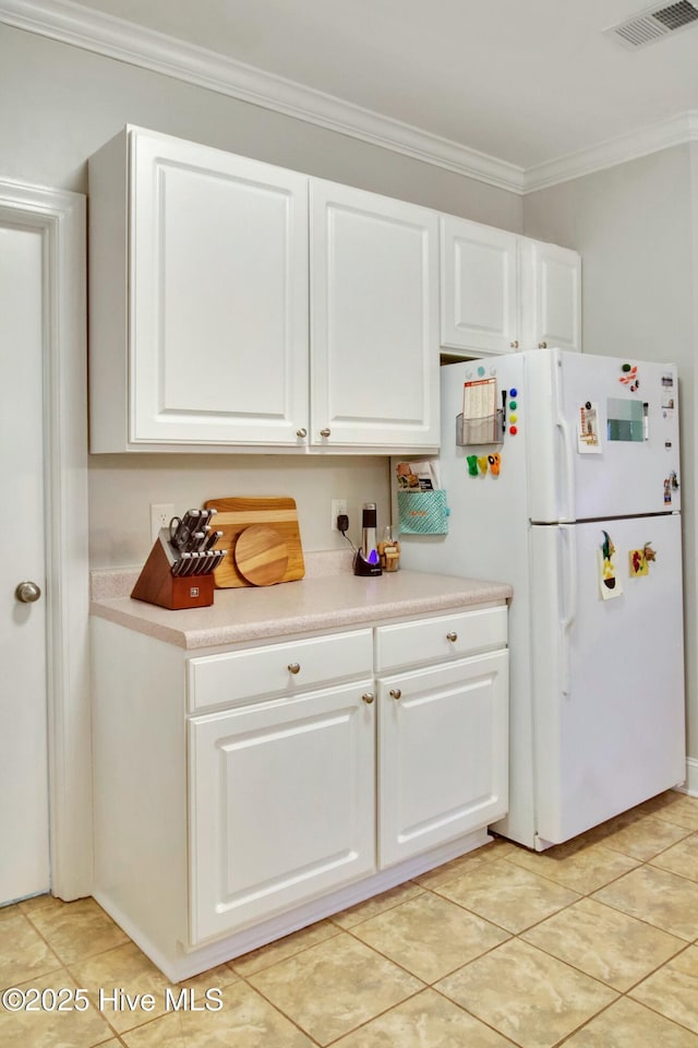 kitchen featuring ornamental molding, white fridge, light tile patterned floors, and white cabinets