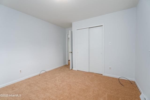 unfurnished bedroom with a closet and light carpet