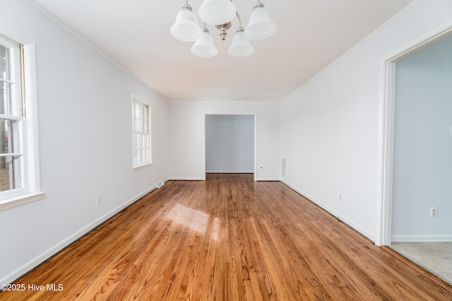 empty room featuring crown molding, a notable chandelier, and light hardwood / wood-style floors