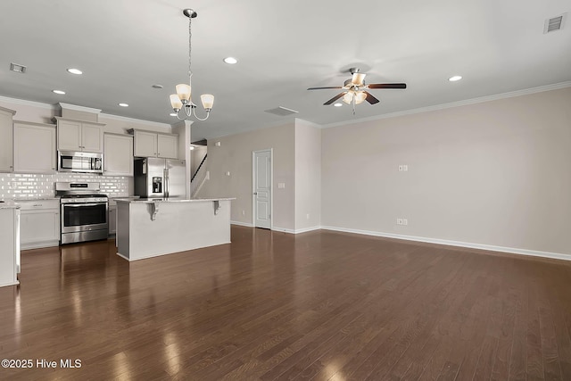 kitchen featuring a center island, a kitchen breakfast bar, pendant lighting, stainless steel appliances, and backsplash