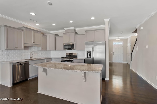 kitchen with light stone counters, appliances with stainless steel finishes, a kitchen bar, and a center island