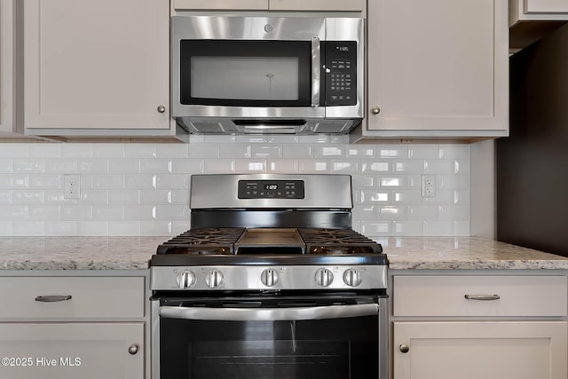 kitchen featuring light stone counters, white cabinetry, stainless steel appliances, and tasteful backsplash