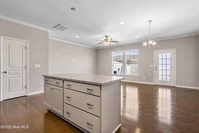 kitchen with a kitchen island, dark hardwood / wood-style floors, decorative light fixtures, white cabinets, and crown molding