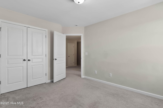 unfurnished bedroom featuring light colored carpet and a closet